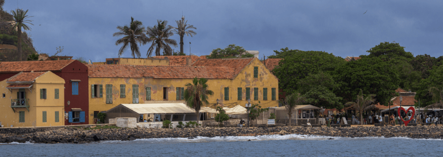 Vista de la isla Gorée desde el barco, al fondo sus casas de colores , palmeras y el monumento al Amor, el corazón
