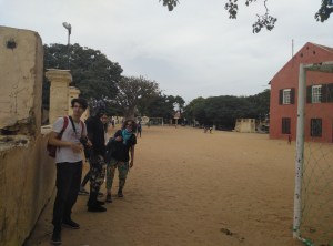 Viajeros en un campo de futbol de Senegal, los niños jugando al fondo