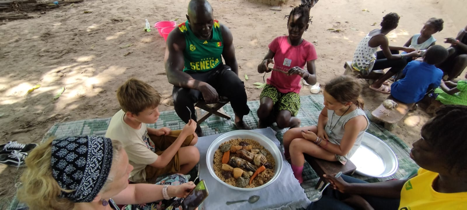Sentados en el exterior en una casa familiar preparados para degustar la gastronomía senegalesa